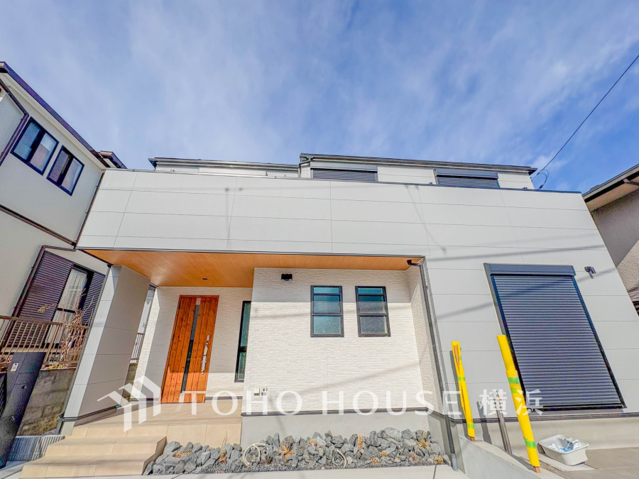 シンプルでモダンなデザインの邸宅。ゆとりある玄関ポーチと木製ドアが温かみを演出します。