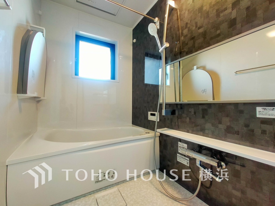 清潔感あふれる白とダークカラーのコントラストが美しい、機能的で快適なバスルームです。