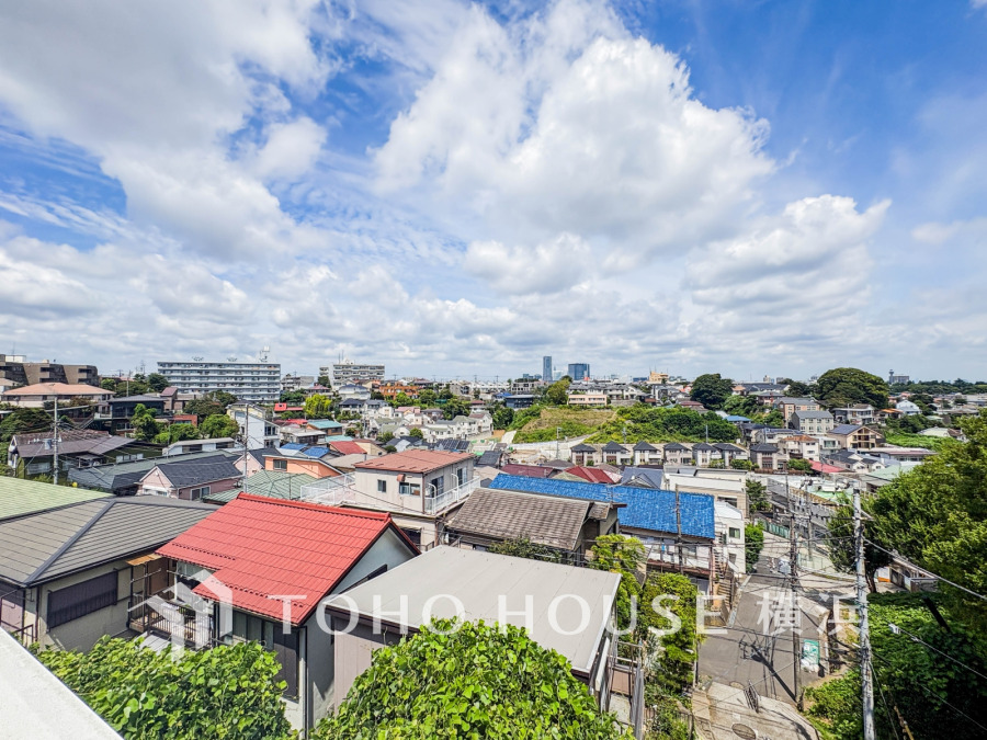 緑豊かな丘陵地に広がる住宅街。多彩な屋根色が街並みに彩りを添え、晴天の空が開放感を演出しています。