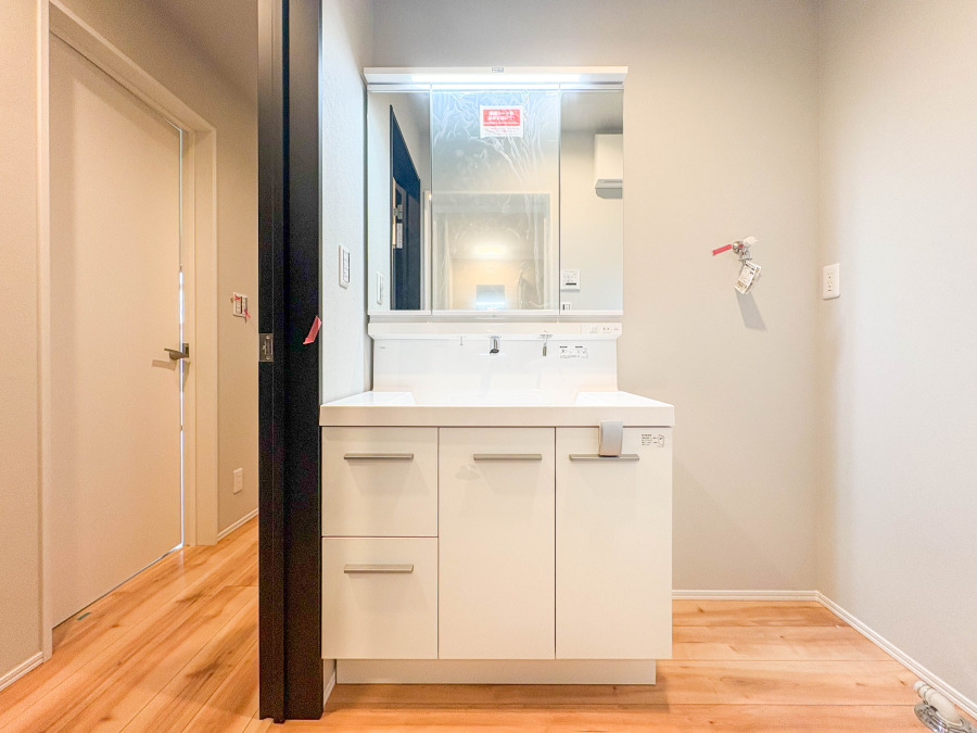 清潔感あふれるホワイトの洗面台は大きな鏡で使いやすく、収納力も十分な機能的な空間です。