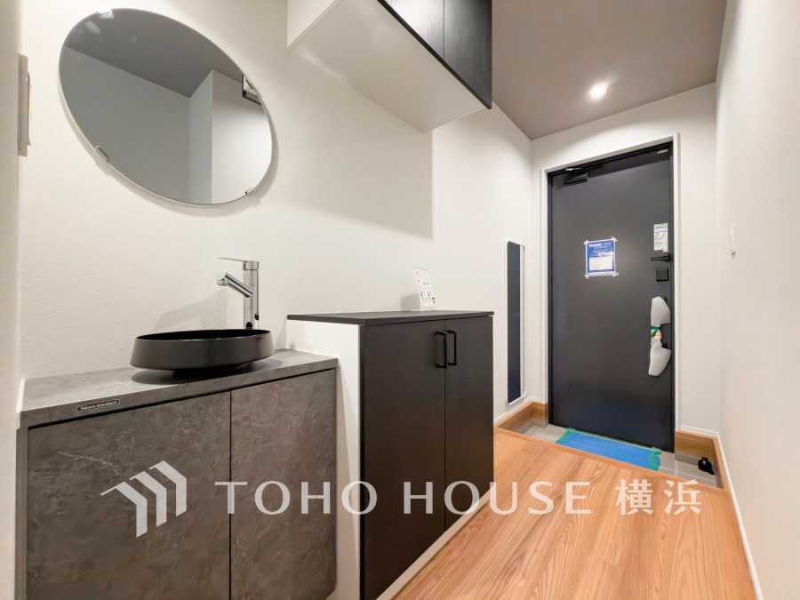 豊かなプライベートタイムへ誘うモダンテイストな玄関。デザインや素材が美しい調和を奏でている空間。入ってすぐに洗面台もあり、帰宅後すぐに手洗いうがいができる清潔なスタイル。