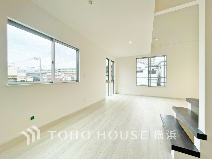 明るい自然光が差し込む広々としたリビング。シンプルな白壁と木目調フローリングで清潔感あふれる空間です。