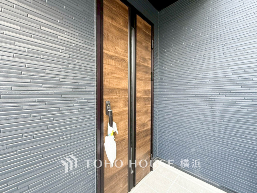 木目調の玄関ドアが映えるスタイリッシュな外壁デザイン。落ち着いた色合いで上質な印象を演出しています。