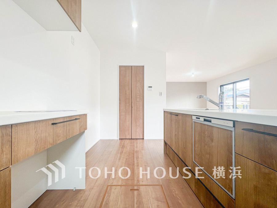 木目調の収納と明るい白を基調とした、開放感あふれるモダンなキッチン空間です。自然光が心地よく差し込みます。