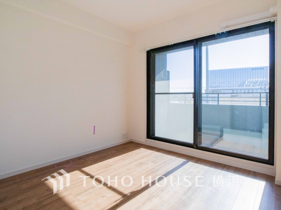 大きな窓から光が差し込む明るい洋室。バルコニーに面し、開放感あふれる快適な空間です。