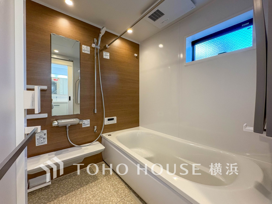 木目調のアクセントパネルが温かみを演出するバスルーム。窓付きで換気も安心です。