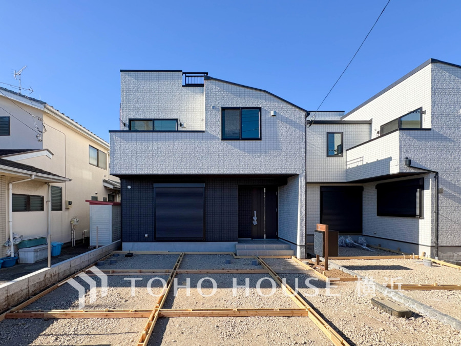 洗練されたデザインの１号棟が、青空の下で輝きます。これから創り上げる庭や駐車場で、家族の夢が広がりますね。