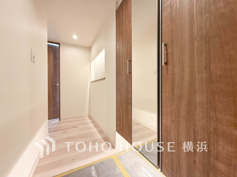 木目調の扉と大きな鏡が備わった上質感のある玄関ホール。