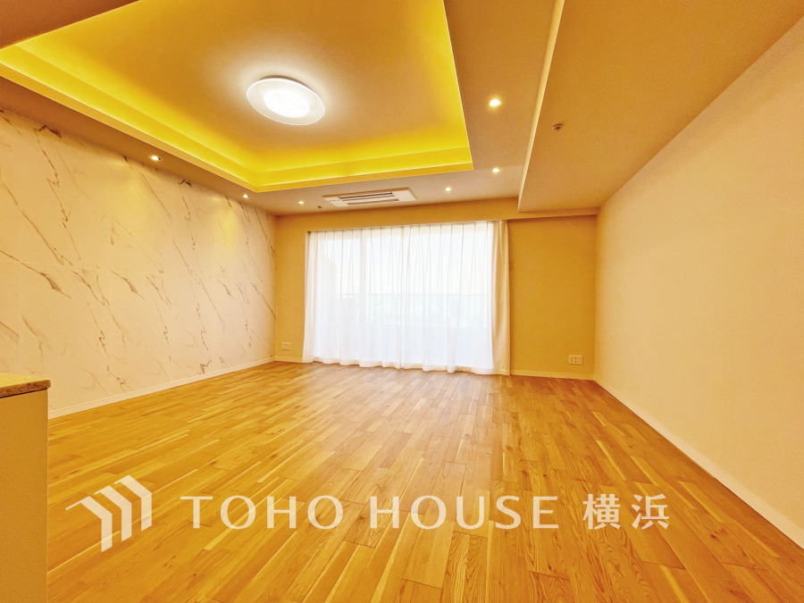 間接照明が美しい天井と大理石調のアクセントウォールが魅力の、明るく開放的なリビング空間です。