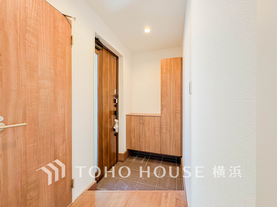 木目調の玄関ドアと収納が調和した、明るく清潔感のある玄関スペース。ゆとりある設計で使い勝手も良好です。