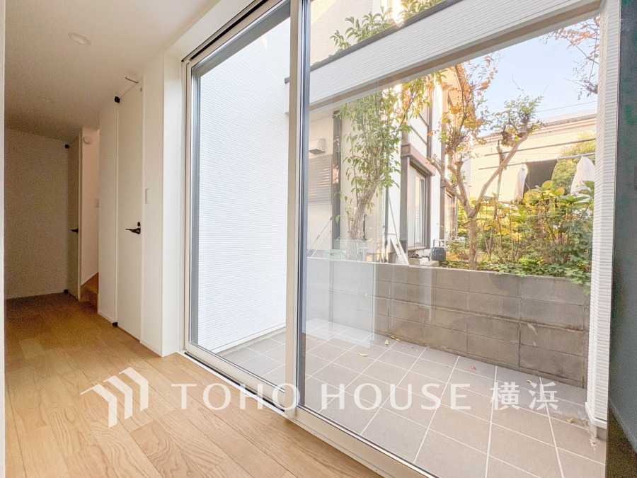 大きな窓から陽光が差し込み、庭を望む明るく開放的なリビングスペース。自然を身近に感じられます。