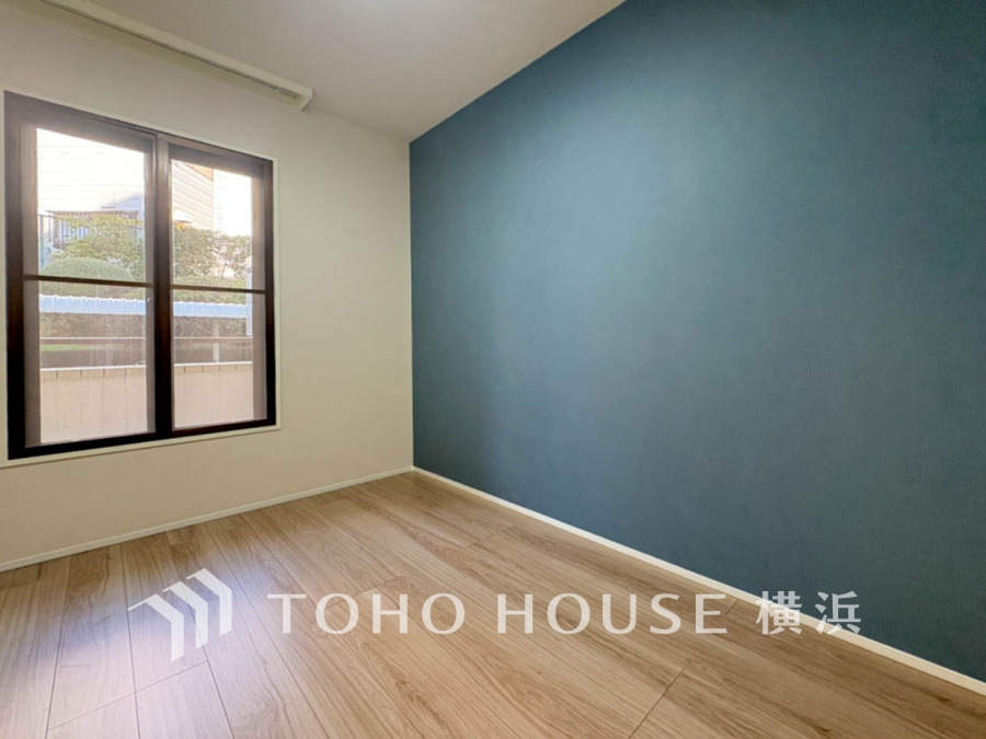 落ち着いたブルーのアクセントクロスが魅力の明るい洋室。自然光が差し込み、快適な空間を演出します。