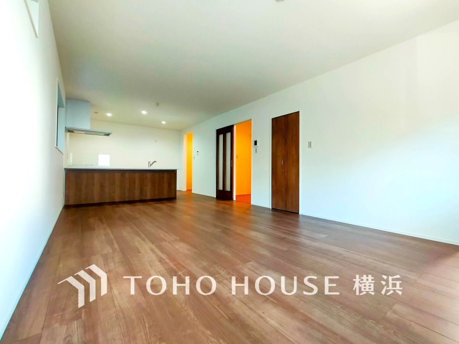 広々としたリビングは木目調の床が温かみを演出し、開放的なキッチンと繋がる快適な空間です。