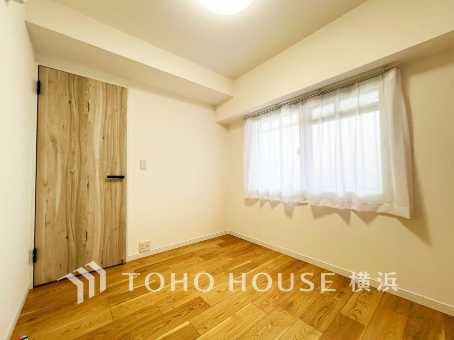 木目調のドアとナチュラルなフローリングが温かみを演出する、明るくシンプルな居室空間です。