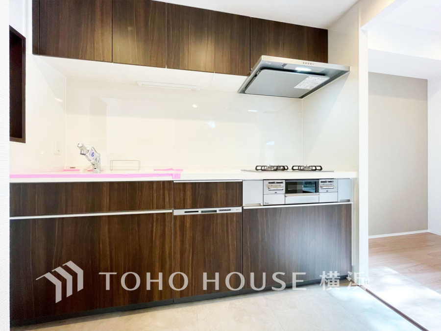 落ち着いた木目調のシステムキッチンは収納豊富で使いやすく、清潔感のある明るい空間を演出します。