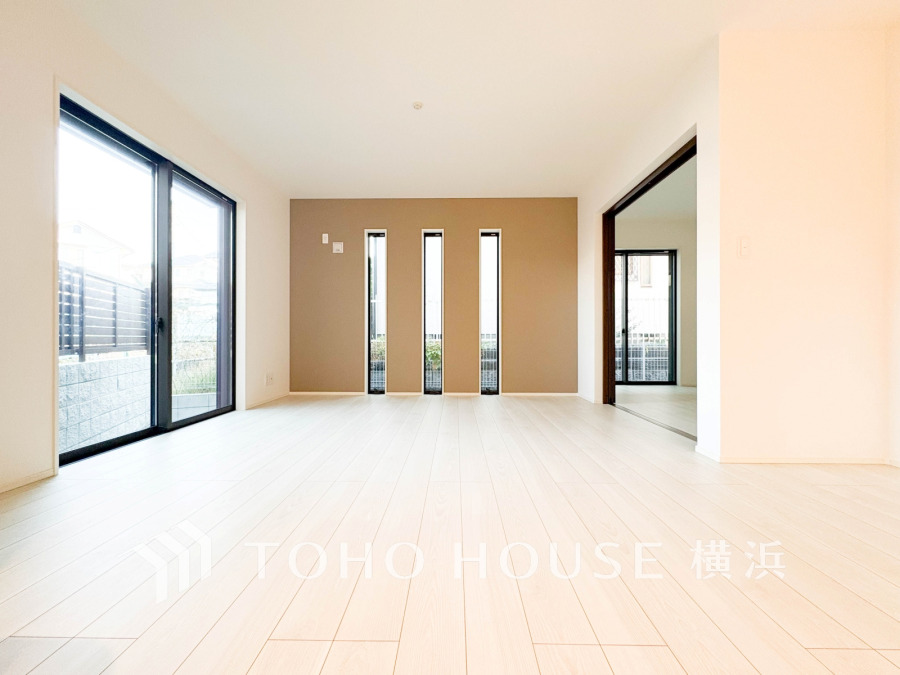 明るい光が差し込む広々としたリビング。モダンなアクセントウォールと大きな窓で開放感あふれる空間です。