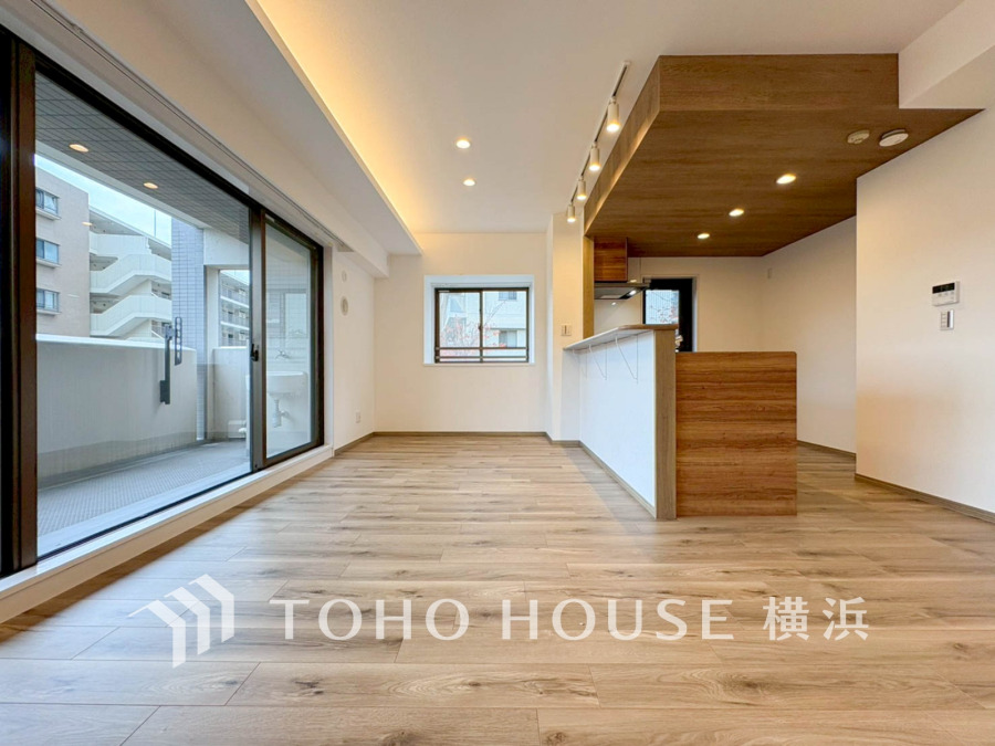 広々としたリビングは大きな窓で明るく開放感があり、木目調の天井が温かみを演出しています。