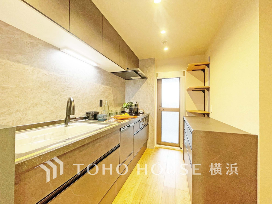 収納豊富で使いやすいシステムキッチン。明るい照明とナチュラルな木目が温かみを演出します。