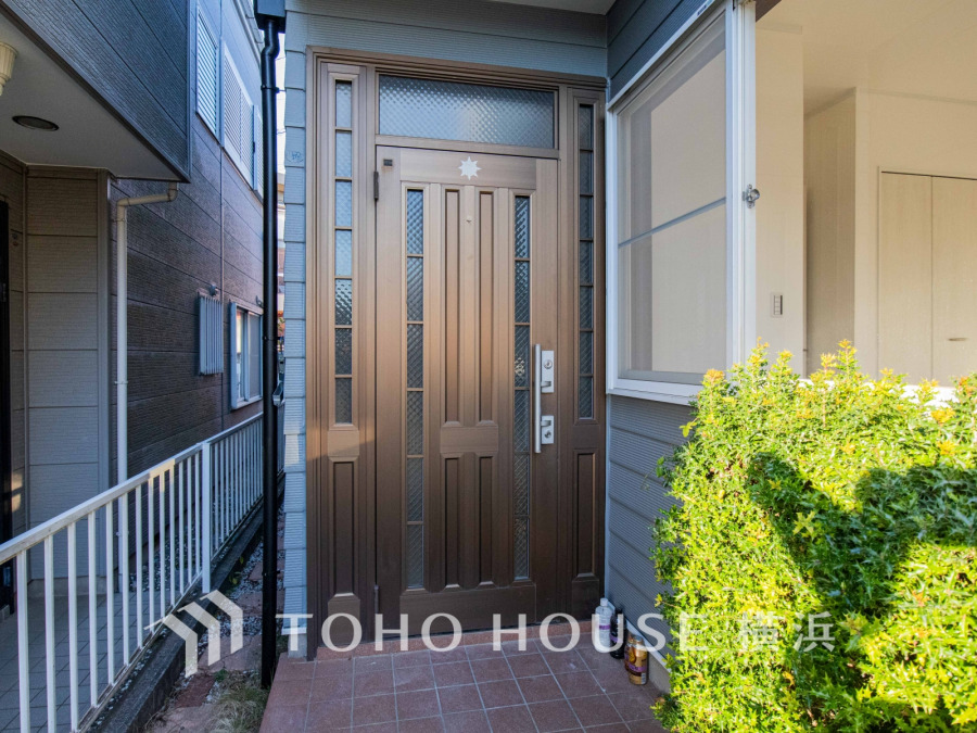 落ち着いたブラウンの玄関ドアと明るい日差しが迎える、温かみのある住まいの入り口です。