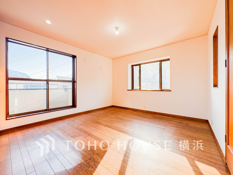 大きな窓から自然光がたっぷり差し込む、温かみのある木目調の床が美しい明るい洋室です。