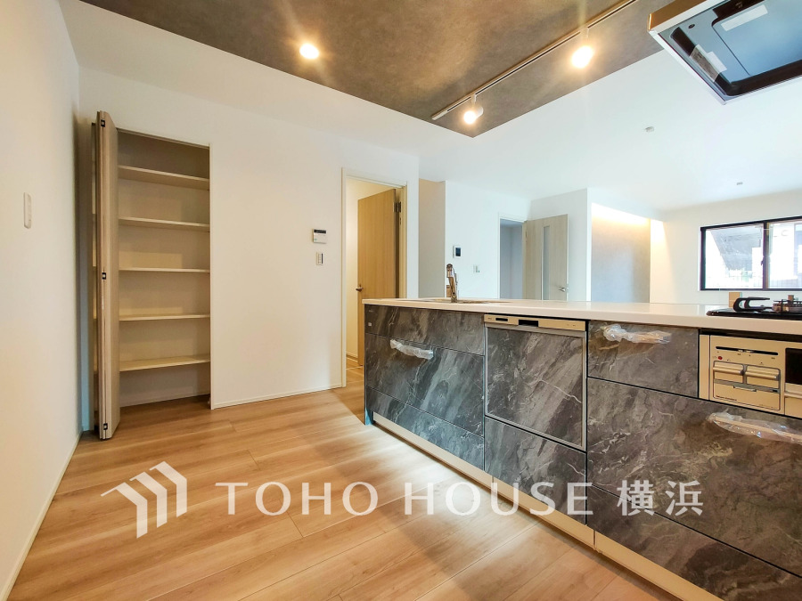 スタイリッシュな大理石調のシステムキッチンと収納豊富なパントリーが魅力のキッチン空間。