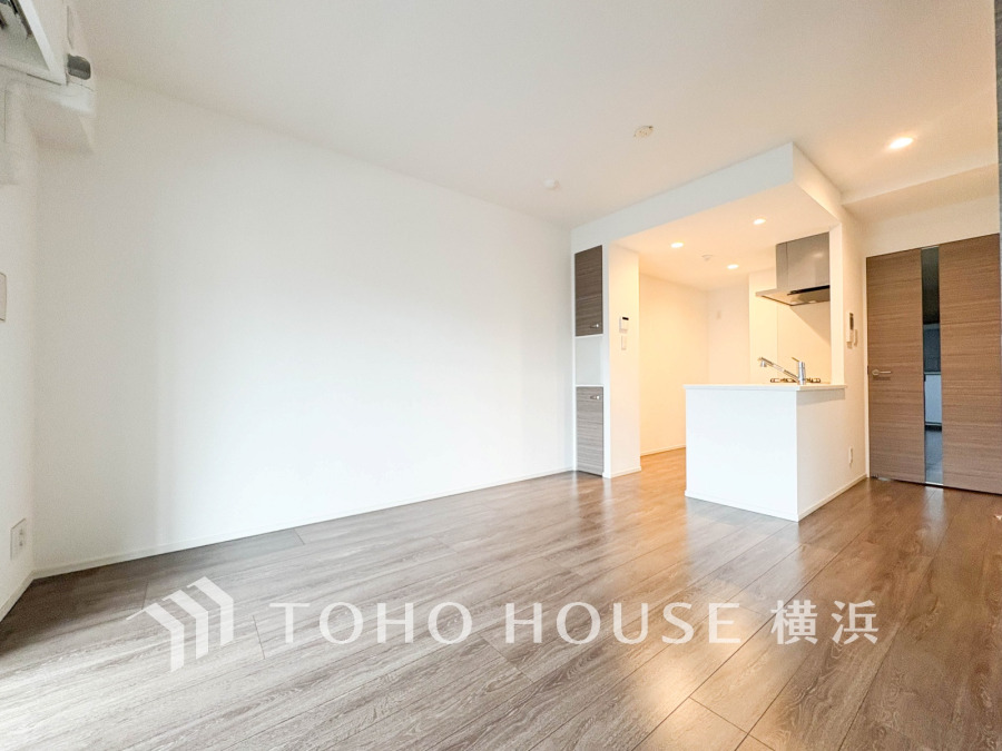 明るい光が差し込む、木目調フローリングの落ち着いたリビング空間。機能的な対面キッチン完備で快適な生活を。