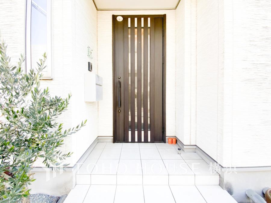 シンプルで清潔感のある玄関ポーチ。縦格子のドアがスタイリッシュな印象を与えます。