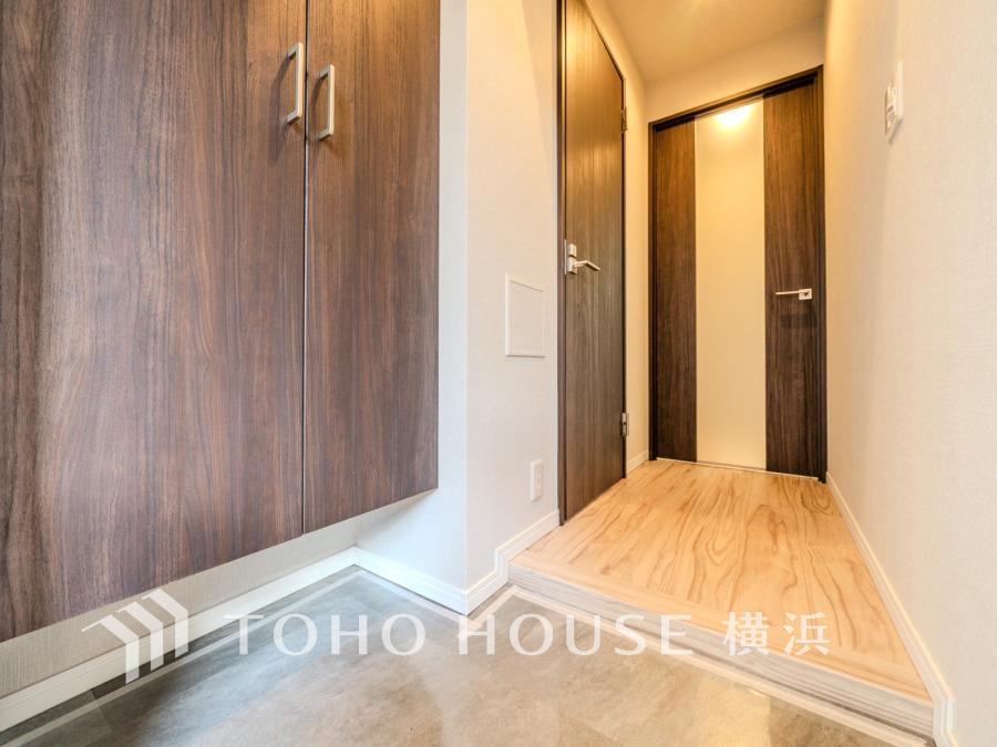 木目調の収納と明るいフローリングが調和した、清潔感あふれる玄関スペースです。収納力も充実しています。