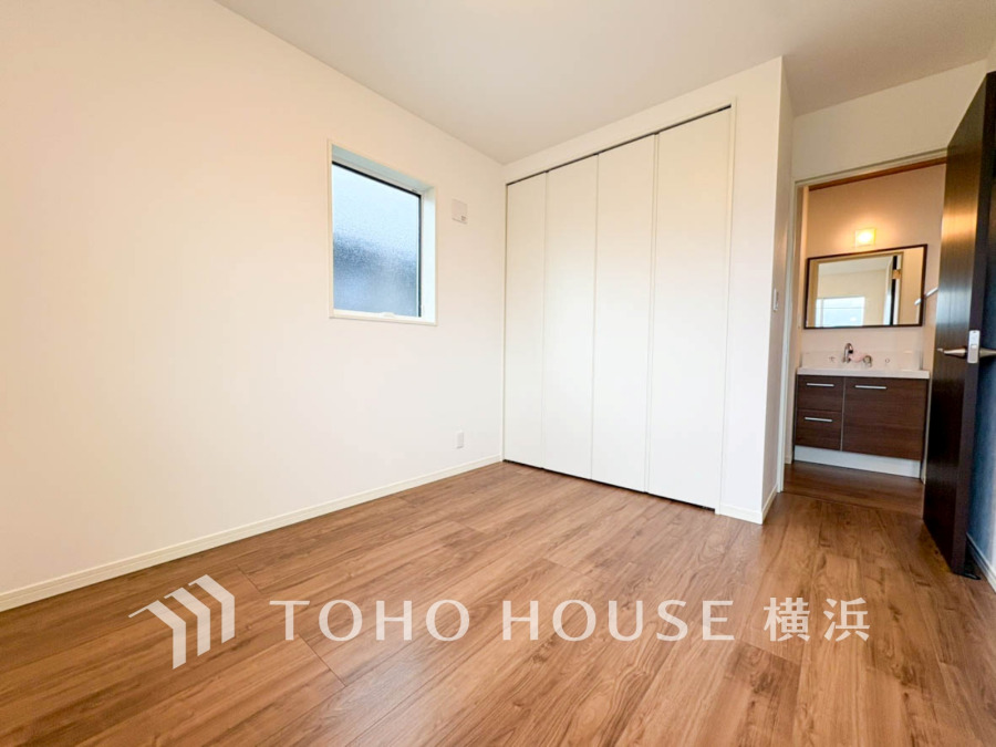 シンプルで清潔感のある洋室。大きな収納と隣接した洗面スペースで使い勝手も良好です。