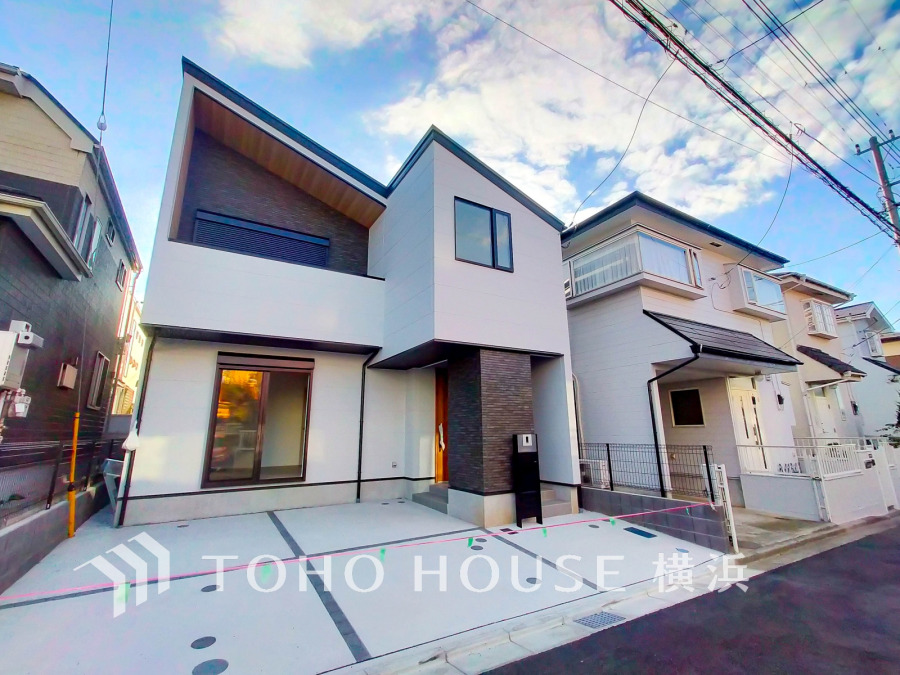 白とダークカラーを基調としたスタイリッシュな外観。広々とした駐車スペースが魅力の新築一戸建てです。