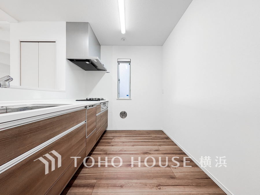 木目調の収納が美しい、清潔感あふれるシステムキッチン。広いスペースで快適な調理が楽しめます。