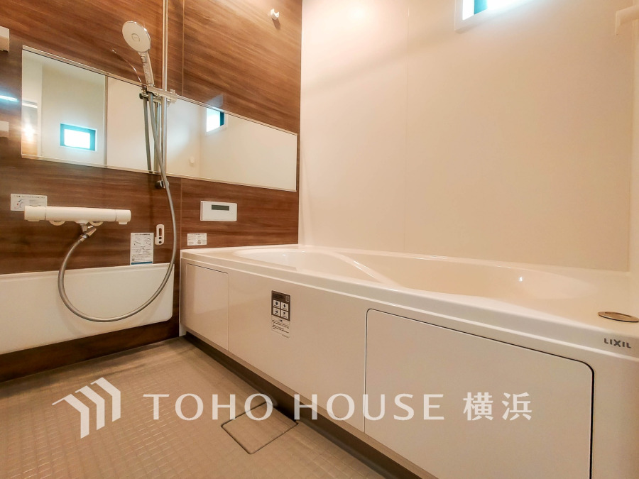 木目調の壁が温かみを演出する、清潔感あふれるゆったりとしたバスルームです。快適なバスタイムをお楽しみください。