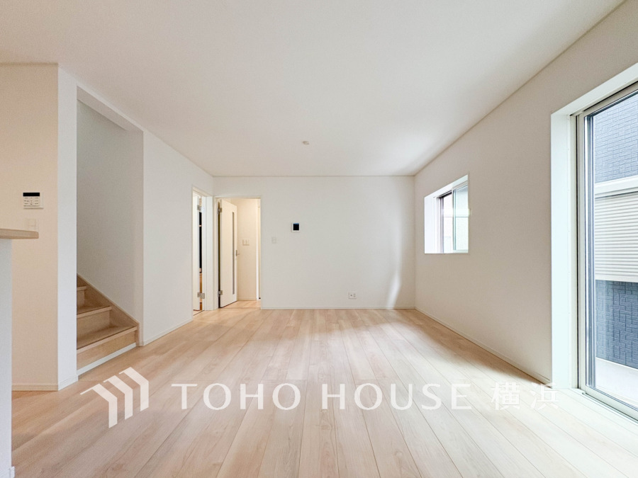 明るい自然光が差し込む、開放感あふれるシンプルで清潔感のあるリビングルームです。