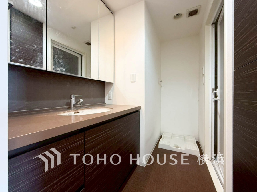 落ち着いたダークカラーの洗面台と収納が備わり、清潔感のあるゆったりとした洗面スペースです。