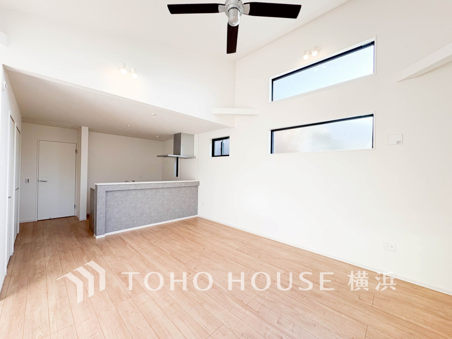 高い天井と横長窓で開放感あふれるリビング。明るい木目床と白壁が調和したモダンな空間です。