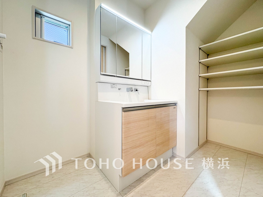 収納力に優れた棚付きの洗面スペース。清潔感ある白を基調とし、快適な生活動線を実現します。