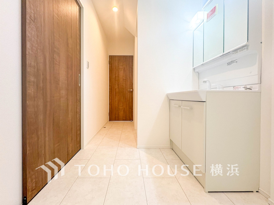 清潔感あふれる洗面スペース。木目調の扉と白を基調とした明るい空間で、快適な毎日をサポートします。