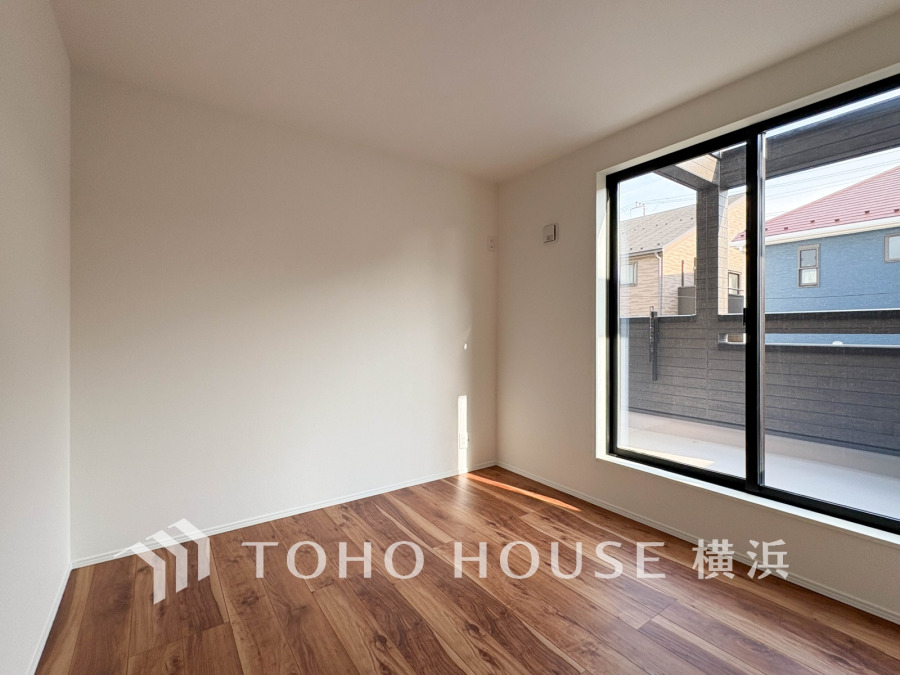 陽光が差し込む広々とした洋室。落ち着いた木目調のフローリングが温かみを演出します。