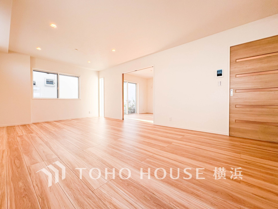 明るい自然光が差し込む、広々とした木目調フローリングのリビングスペースです。