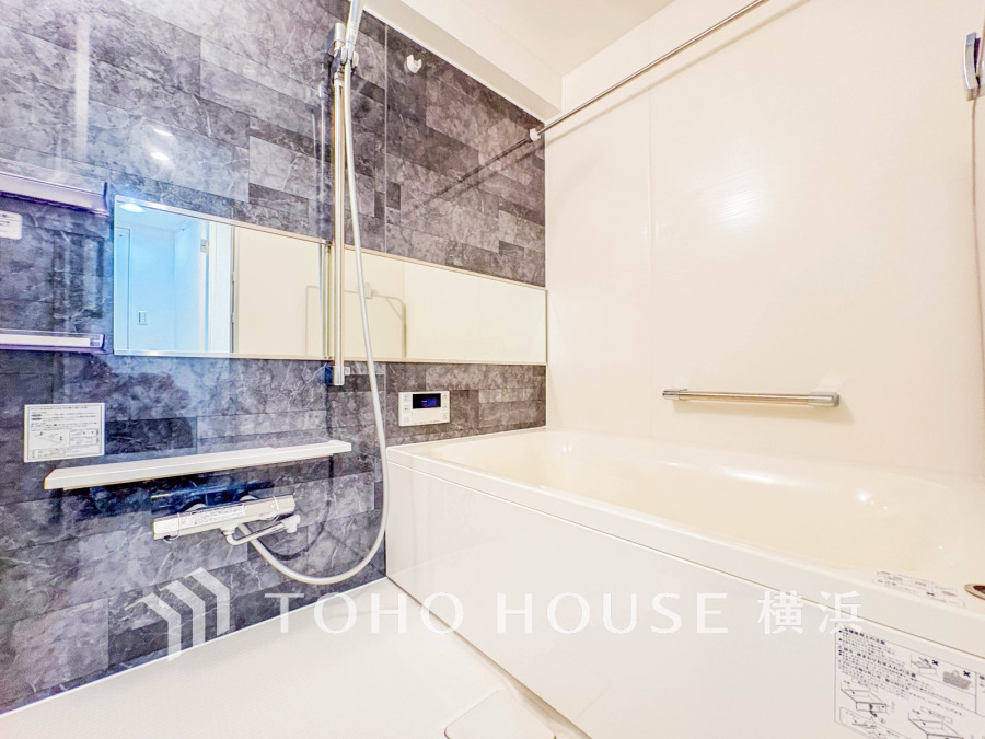 高級感ある石目調の壁パネルが映える、ゆったり入浴できる快適なバスルーム空間です。