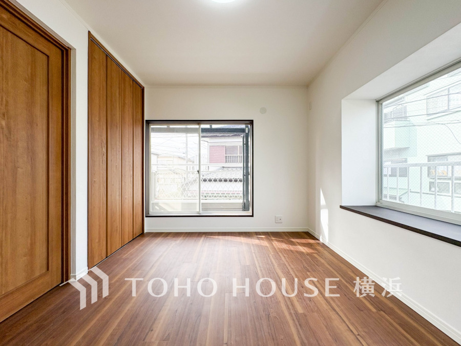 明るい自然光が差し込む、木目調の床と収納扉が温かみを感じさせるシンプルで使いやすい居室です。