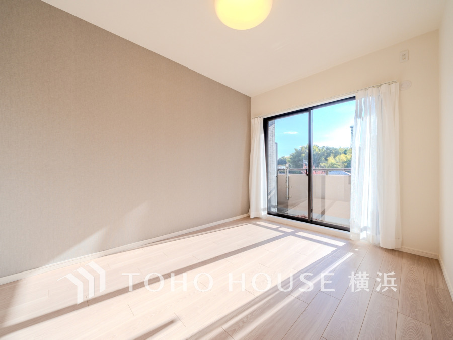 大きな窓からたっぷりの陽光が差し込む明るい洋室。シンプルで落ち着いた色調が魅力です。