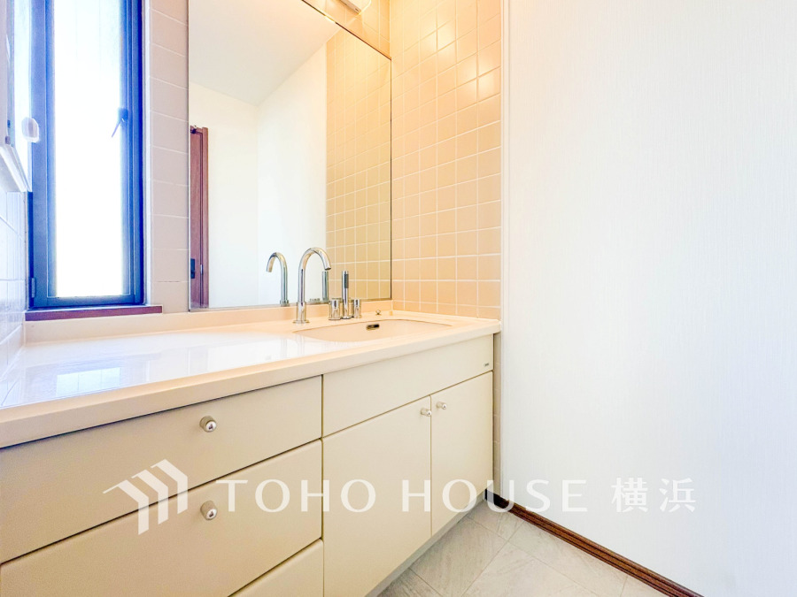 清潔感あふれる洗面スペース。大きな鏡と収納力のあるキャビネットで使い勝手も抜群です。明るい自然光が心地よい空間。