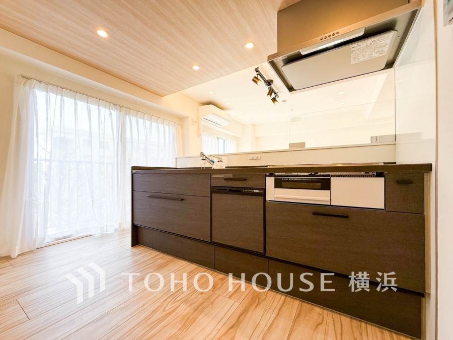 自然光がたっぷり入る明るいキッチン。木目調の床と天井が温かみを演出し、快適な調理空間を実現しています。