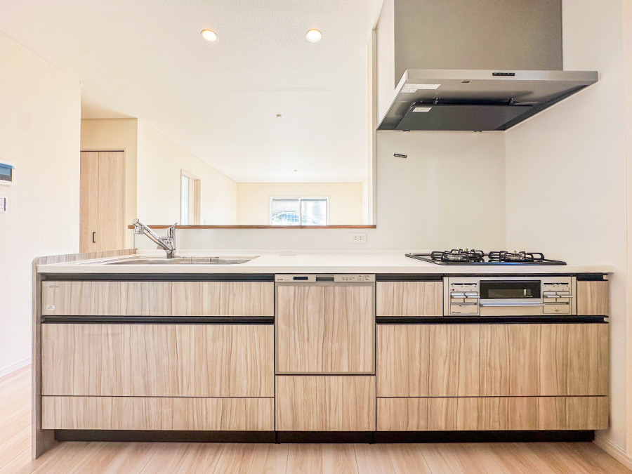 木目調の収納が美しい、使いやすく開放感のあるシステムキッチン。家族との会話も弾む対面式設計です。