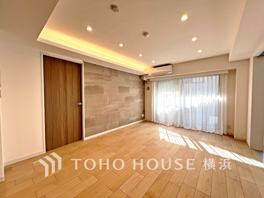 自然光が注ぐ明るいリビング。間接照明とアクセントウォールで落ち着いた空間を演出しています。