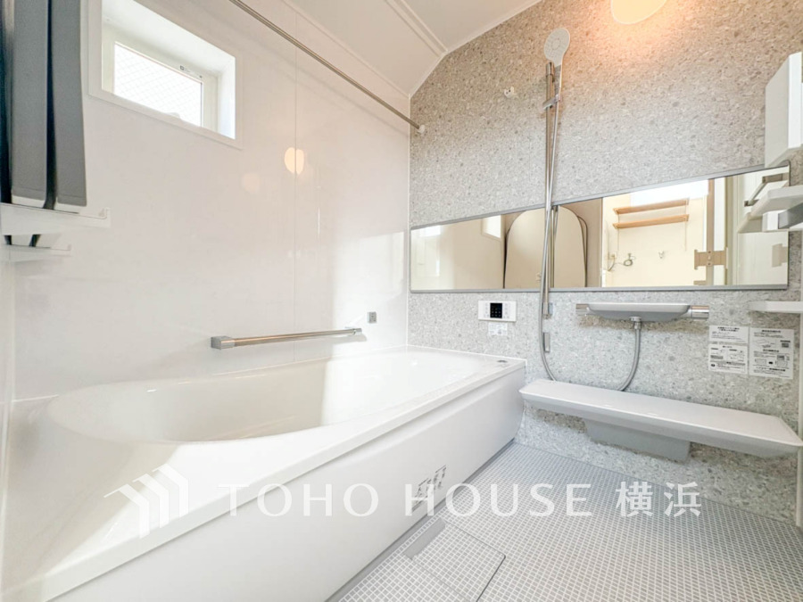 清潔感あふれる白基調のバスルーム。広々とした浴槽と便利な手すり付きで安心してくつろげます。