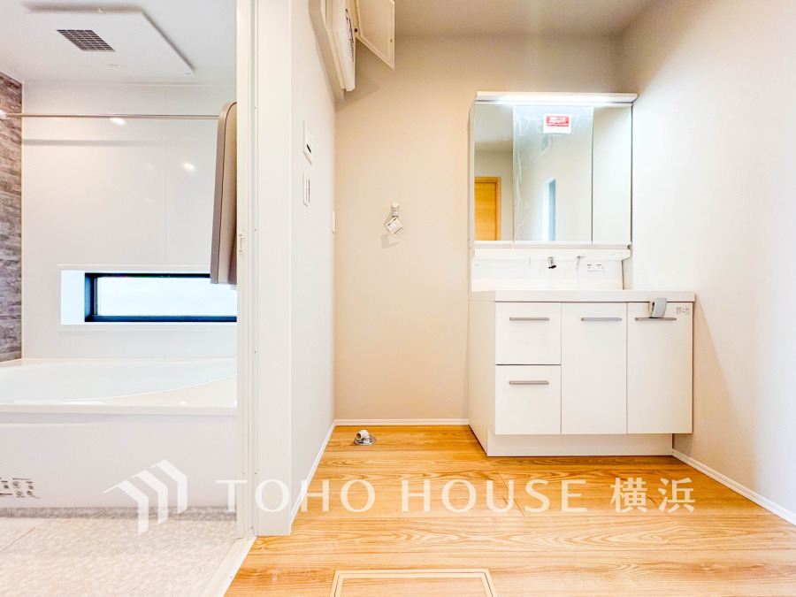 清潔感あふれる洗面所とバスルーム。木目調の床が温かみを演出し、快適な空間を実現しています。