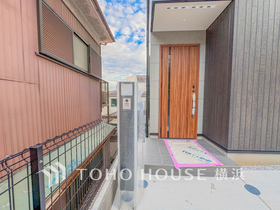 木目調の玄関ドアが印象的な新築住宅のエントランス。モダンな門柱と安心のインターホン付き。