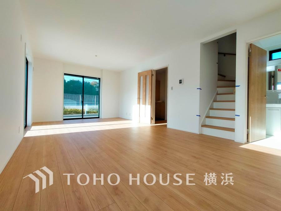 陽光が差し込む開放的なリビング。ナチュラルな木目フローリングと白壁で、温かみのある空間を演出しています。